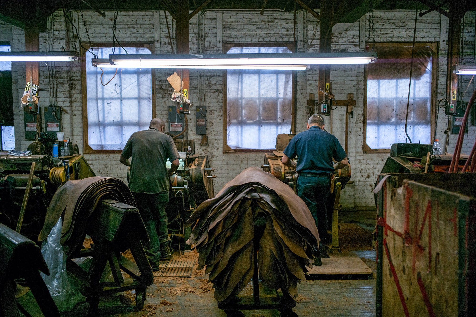 Two men at a tannery process leather hides.
