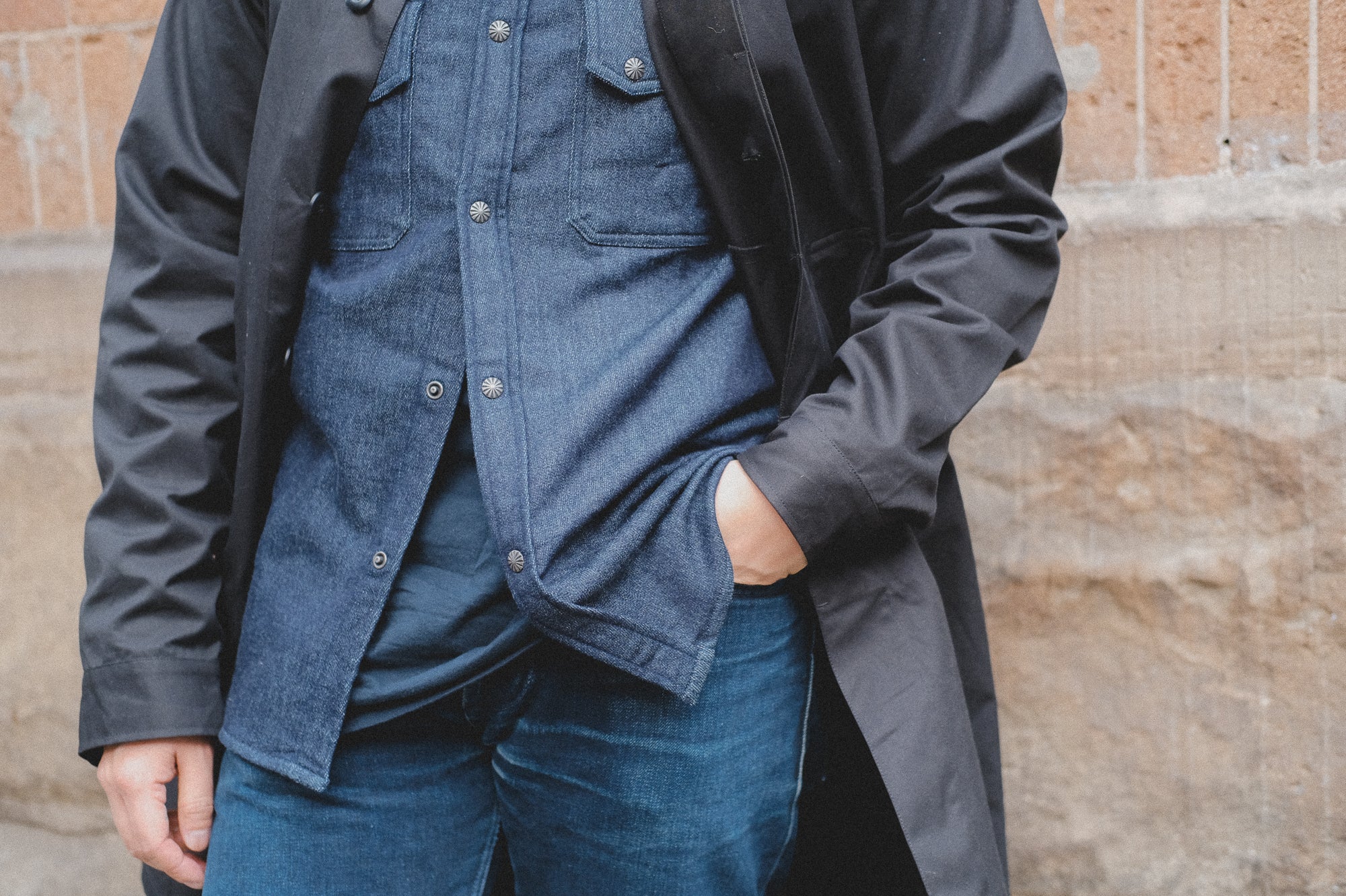 An up-close photo of layers of indigo garments under a black jacket.