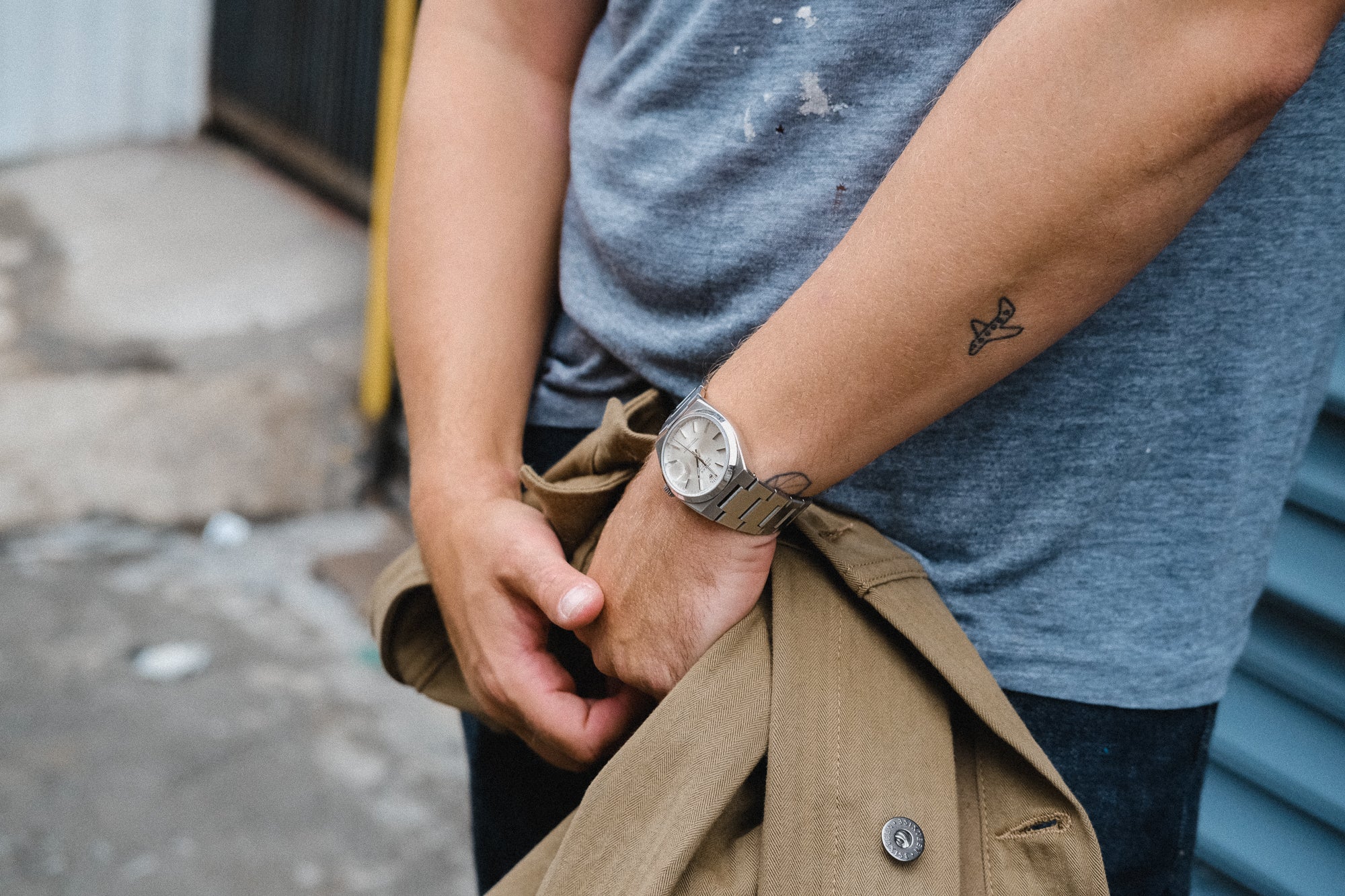 A detailed photo of a man holding a tan jacket. 