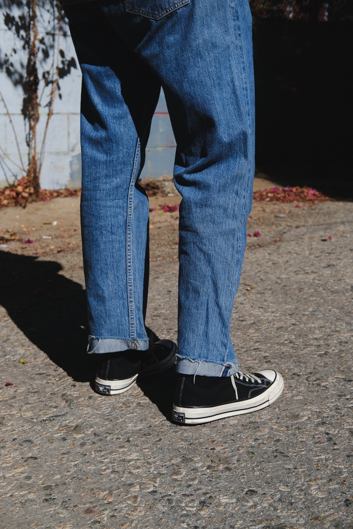 A pair of stonewashed jeans worn with black Converse sneakers.