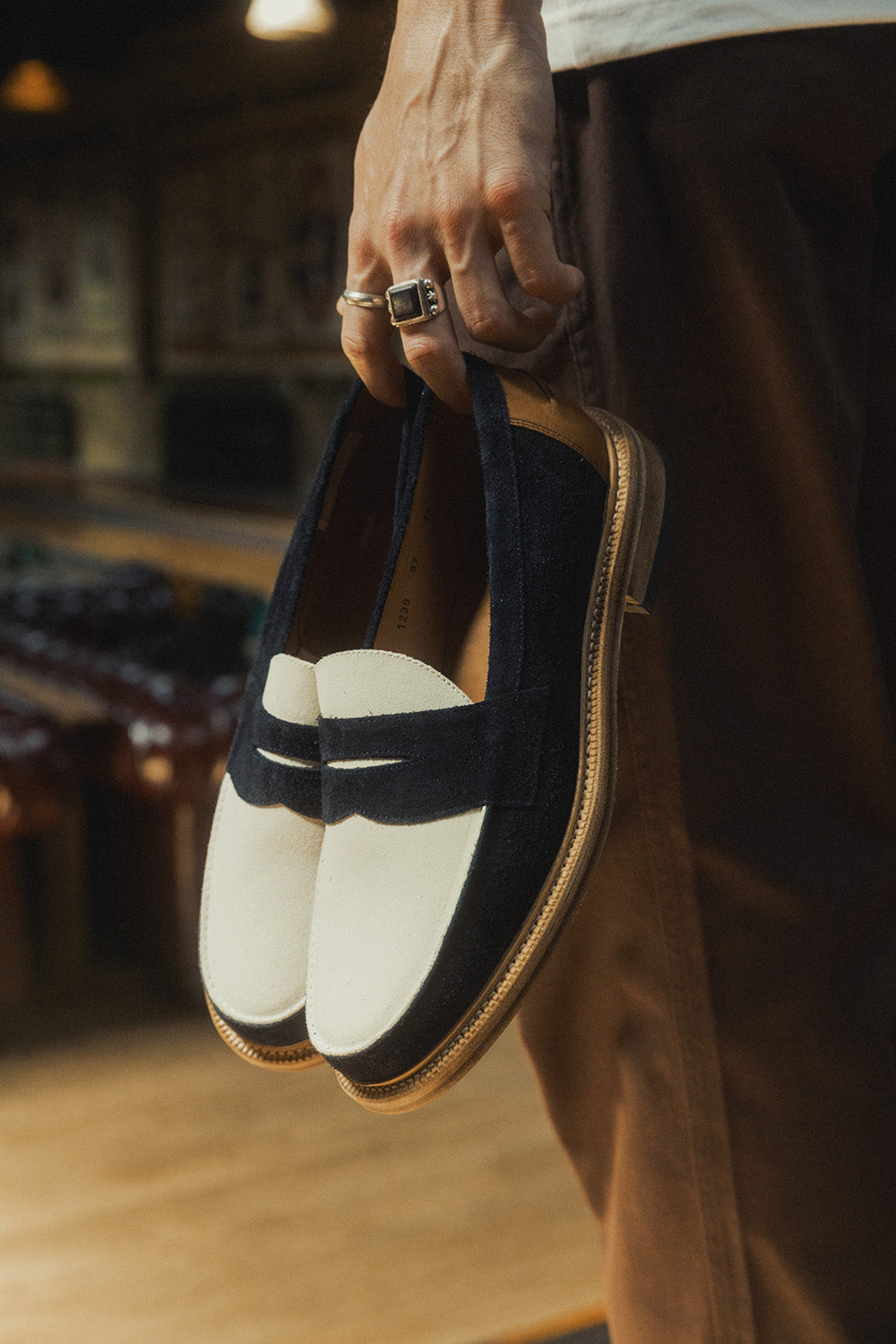 A pair of two tone navy and cream loafers in hand.