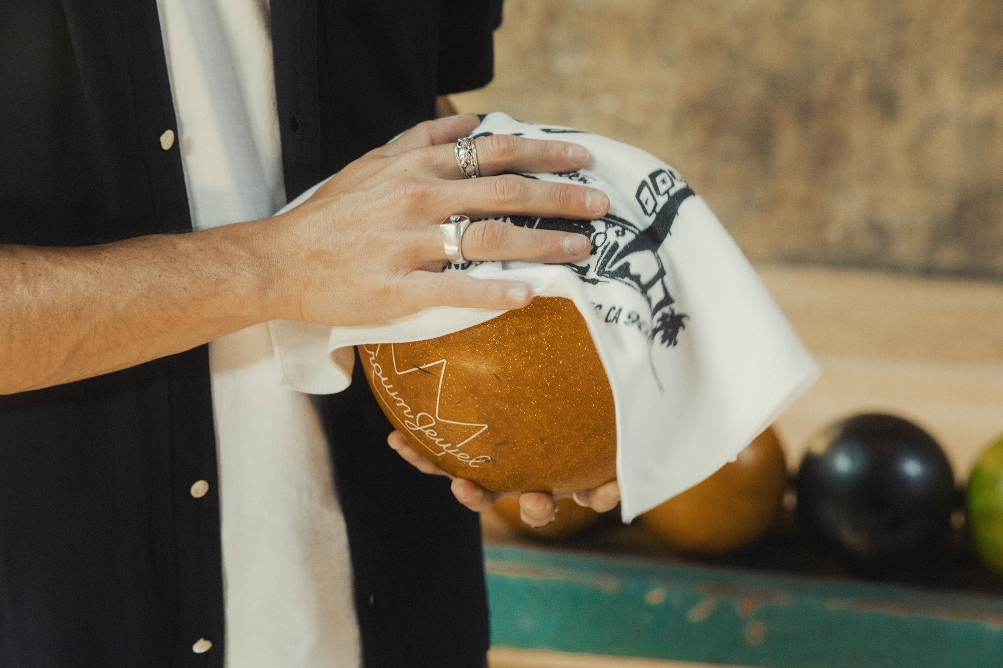 A man polishes his bowling ball with a white towel.