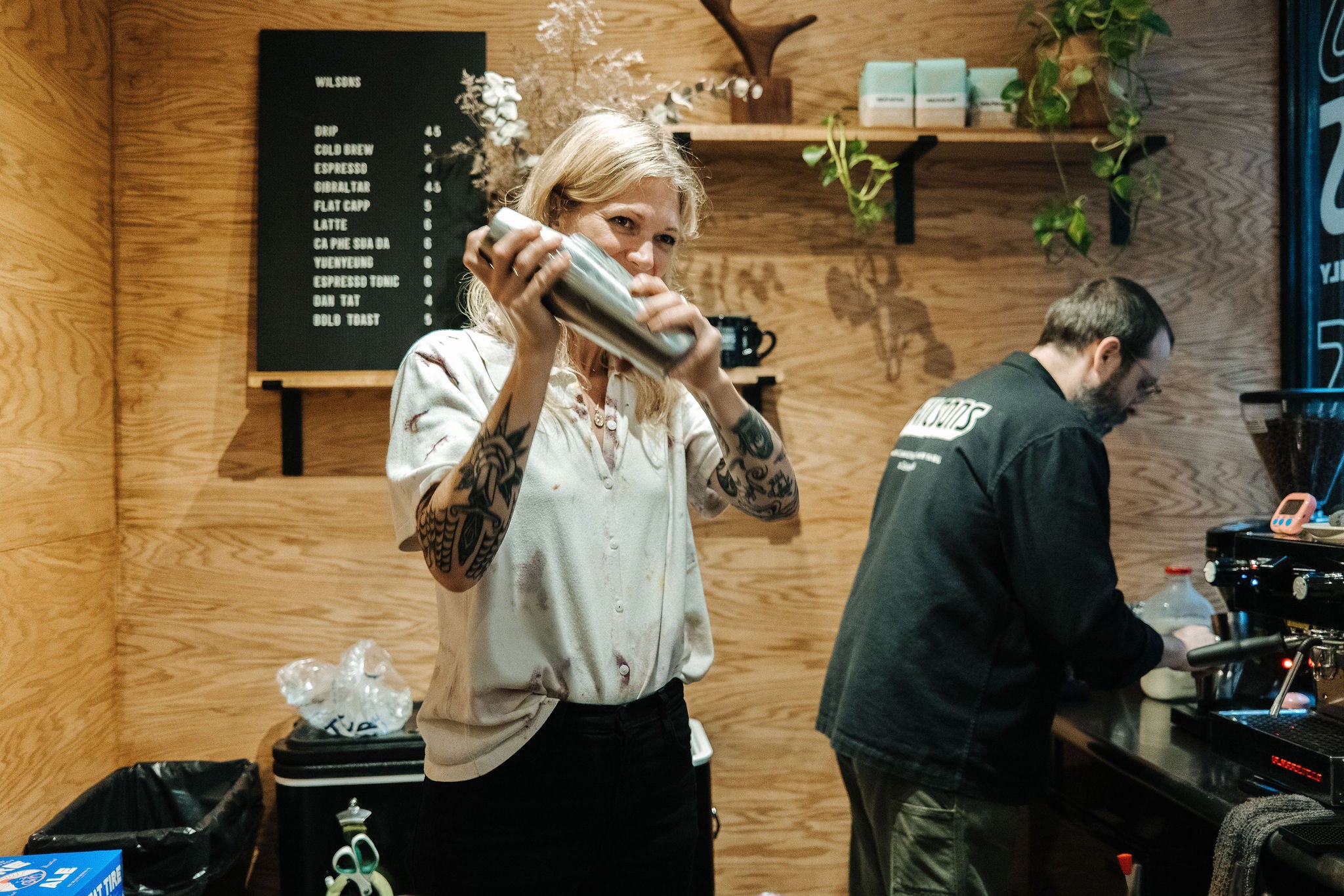 A barista shakes a drink in a shaker.