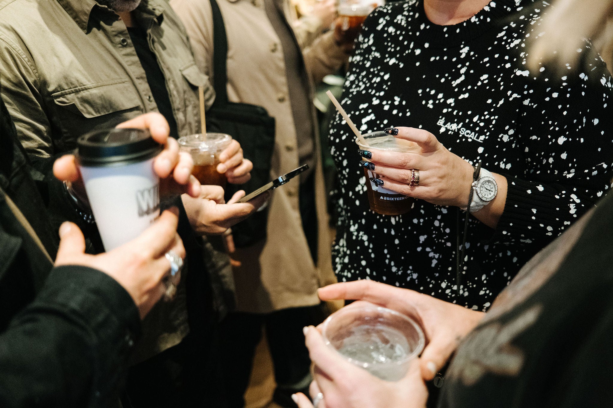 Partygoer hands holding drinks and coffees.