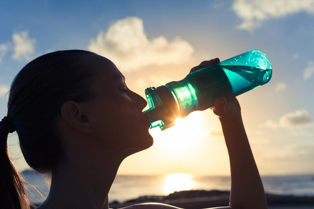Photo of a woman drinking from a water bottle out on a sunny day