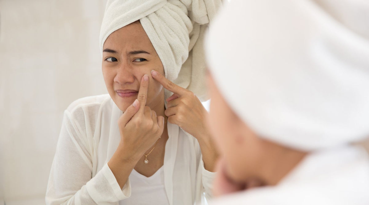 woman picking at acne on skin