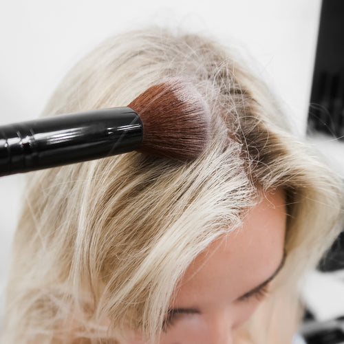 girl applying dry shampoo to hair