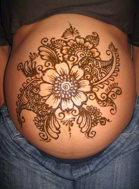 Harmless henna floral drawing art on boho pregnant woman tummy