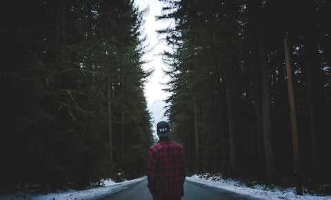 Man wearing flannel with snow on the ground.