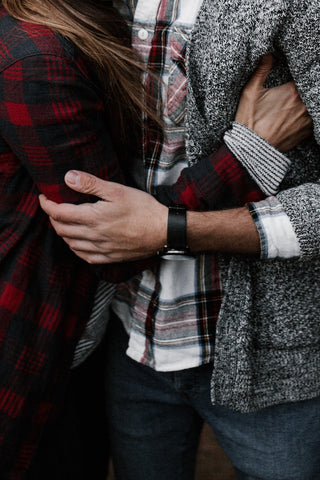 Couple embracing wearing flannel with layers.