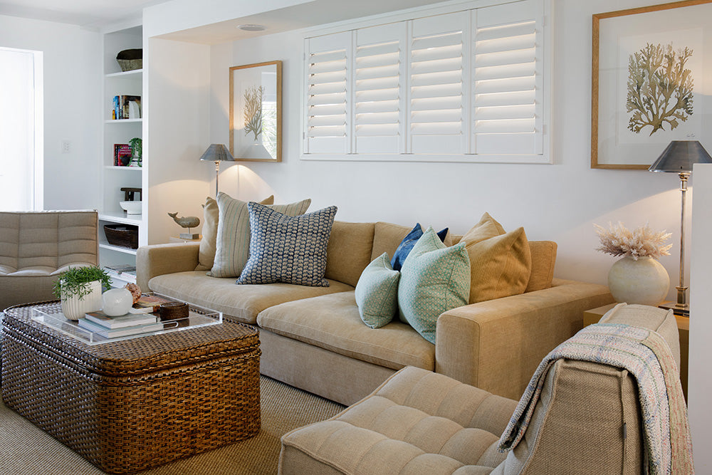 Styling by Rachel Elizabeth Interiors & Textiles. Living room feature beige couch, rattan coffee table, numerous cushions, rug, lamp and wall art