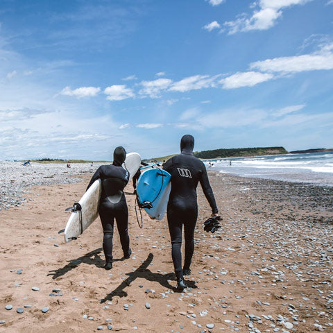 men in cheap wetsuits walking on beach