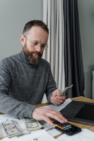 Man in Gray Sweater Computing Money