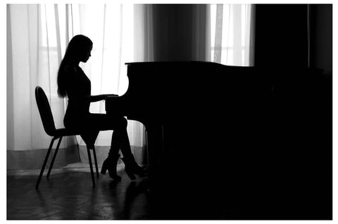 silhouette of a woman sitting at the piano