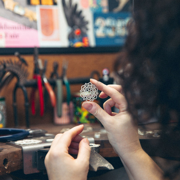 Inspecting mandala pendant silver at jewellers workbench