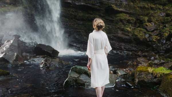 Woman standing underneath waterfall, inspired by the nature that surrounds her