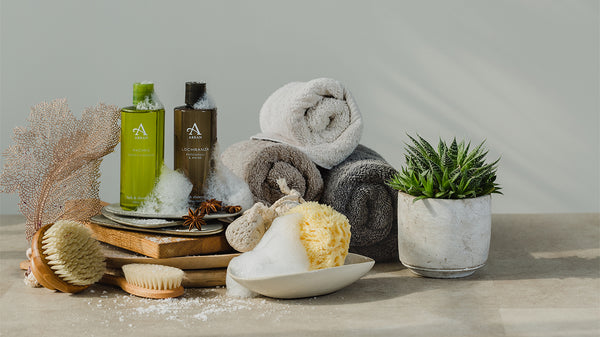 Men's shower gels surrounded by rolls of towels, sponge and shower brushes