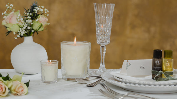 Wedding centrepiece ideas with a vase of flowers, ARRAN Sense of Scotland candles and favours on the dinner plates of ARRAN Sense of Scotland miniature Bath & Shower Gels