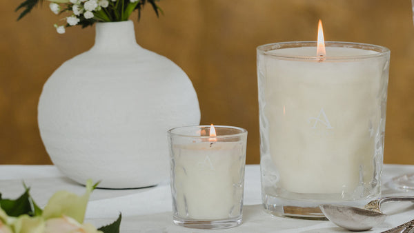 Small 8cl candle next to large 35cl candle, both in matching dimpled glass containers, lit