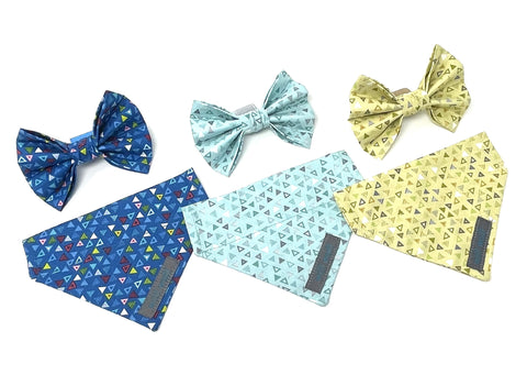 Image shows three handmade dog bows and three handmade dog bandanas made from quality washable cotton in three different colourways. The first is dark blue and has a light blue, white, yellow, pink and red triangle print, the second is lighter blue and has a blue, white and grey triangle print and the third is yellow with white and grey triangles.