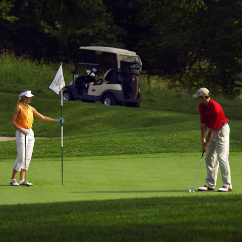 couple golfing with golf cart on golf course