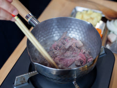 Dorar la carne en una olla japonesa.