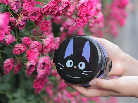 Hands holding a black and purple small bento box with a design of Jiji from Kiki's Delivery Service