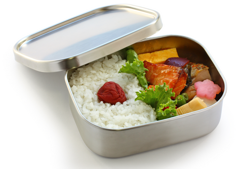Caja bento de metal rellena de arroz blanco, umeboshi, pescado y verduras.
