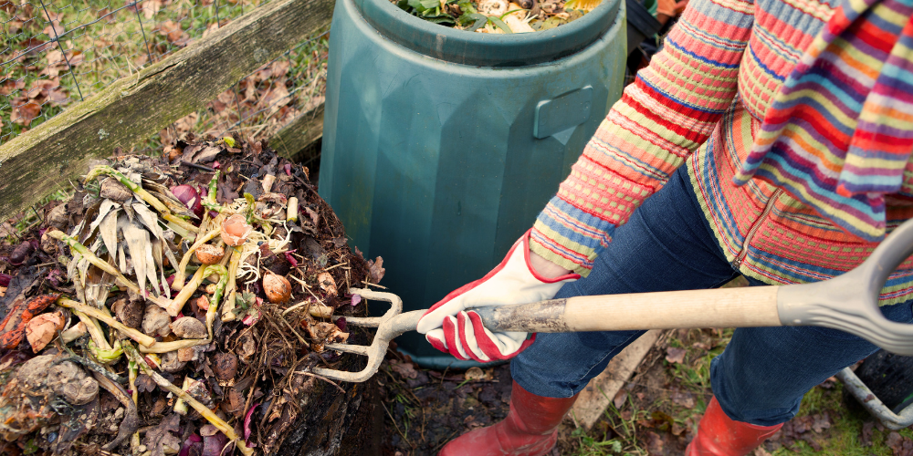 Person mixing up organic waste in a compost pile