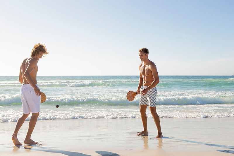 Two men playing Frescobol on the beach