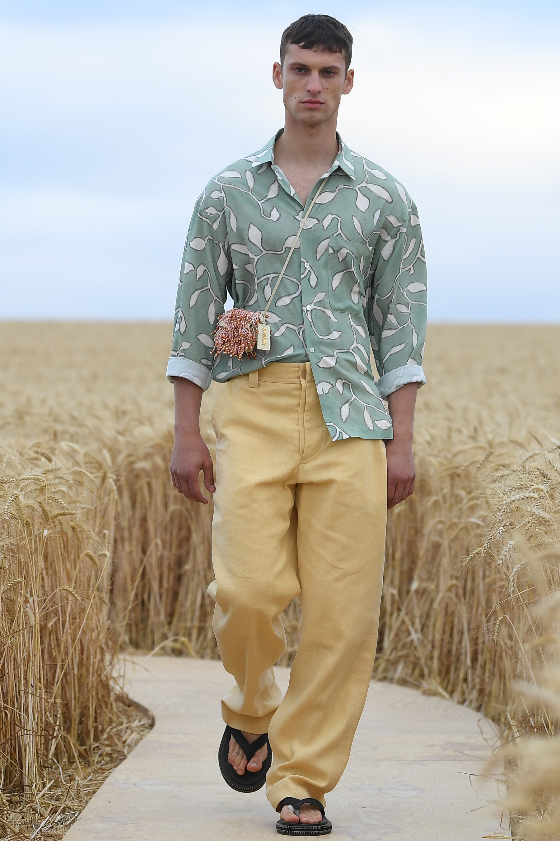 French-Californian styled model wearing baggy trousers a loose patterned button up shirt and flip flops