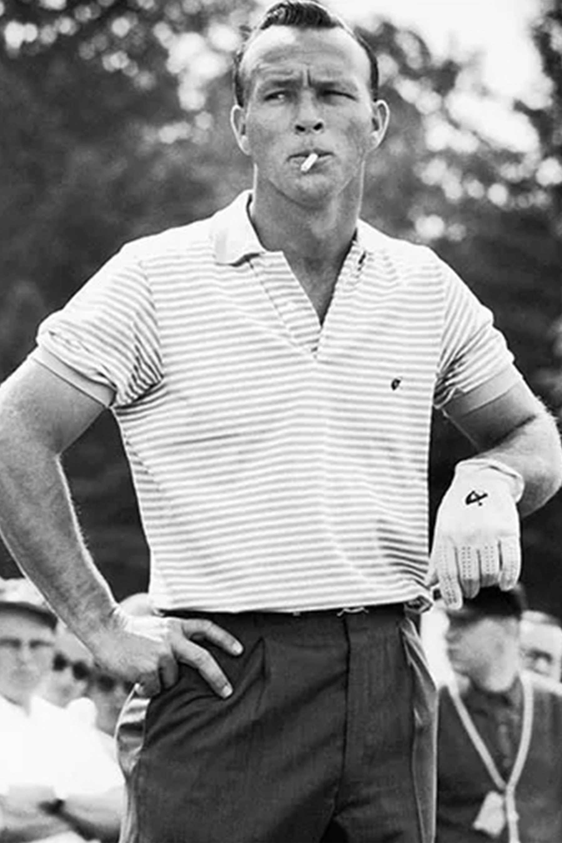 Young Arnold Palmer wearing a striped polo with a cigarette in his mouth