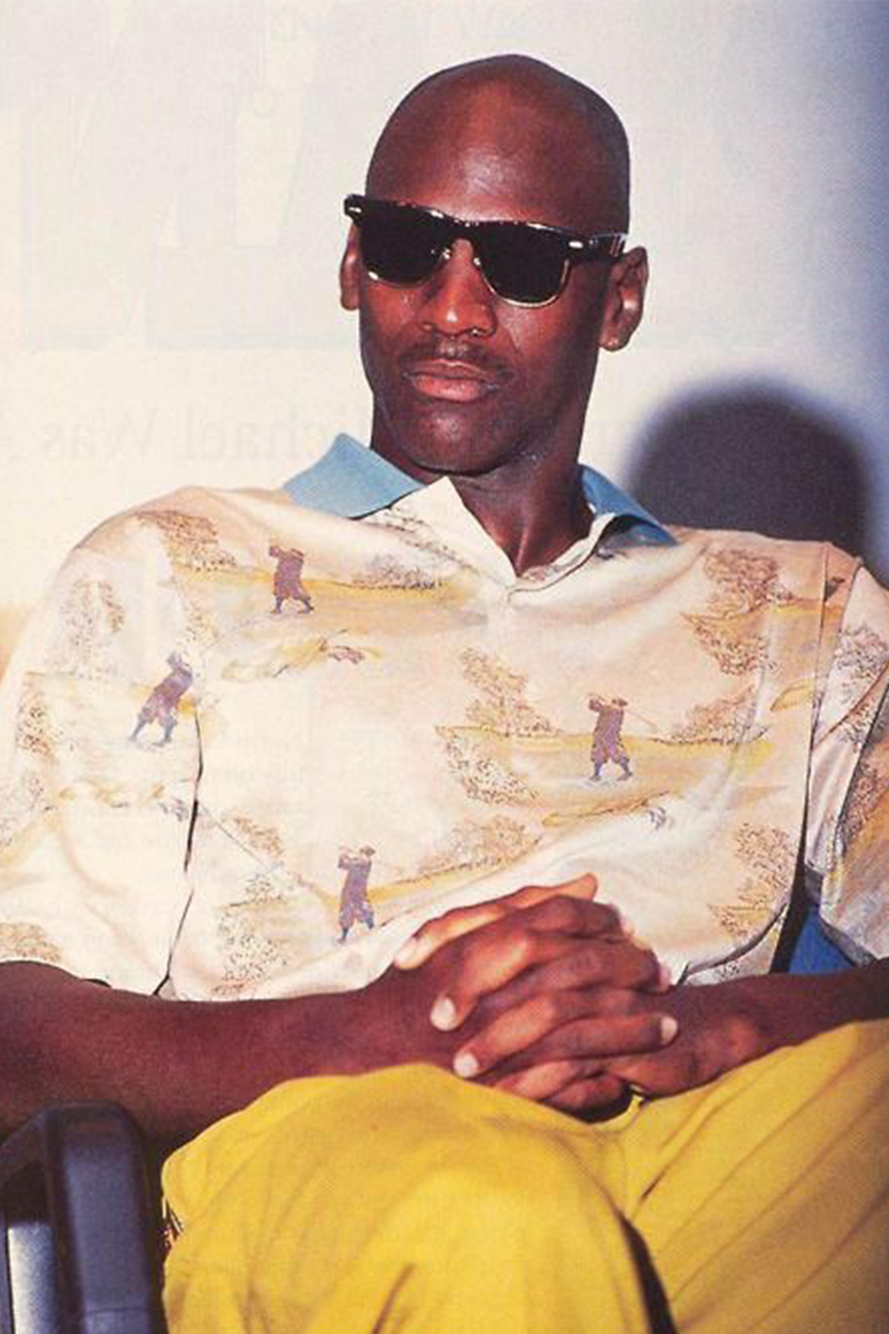 Michael Jordan wearing black Wayfarer-style sunglasses and a golf print polo shirt during an interview