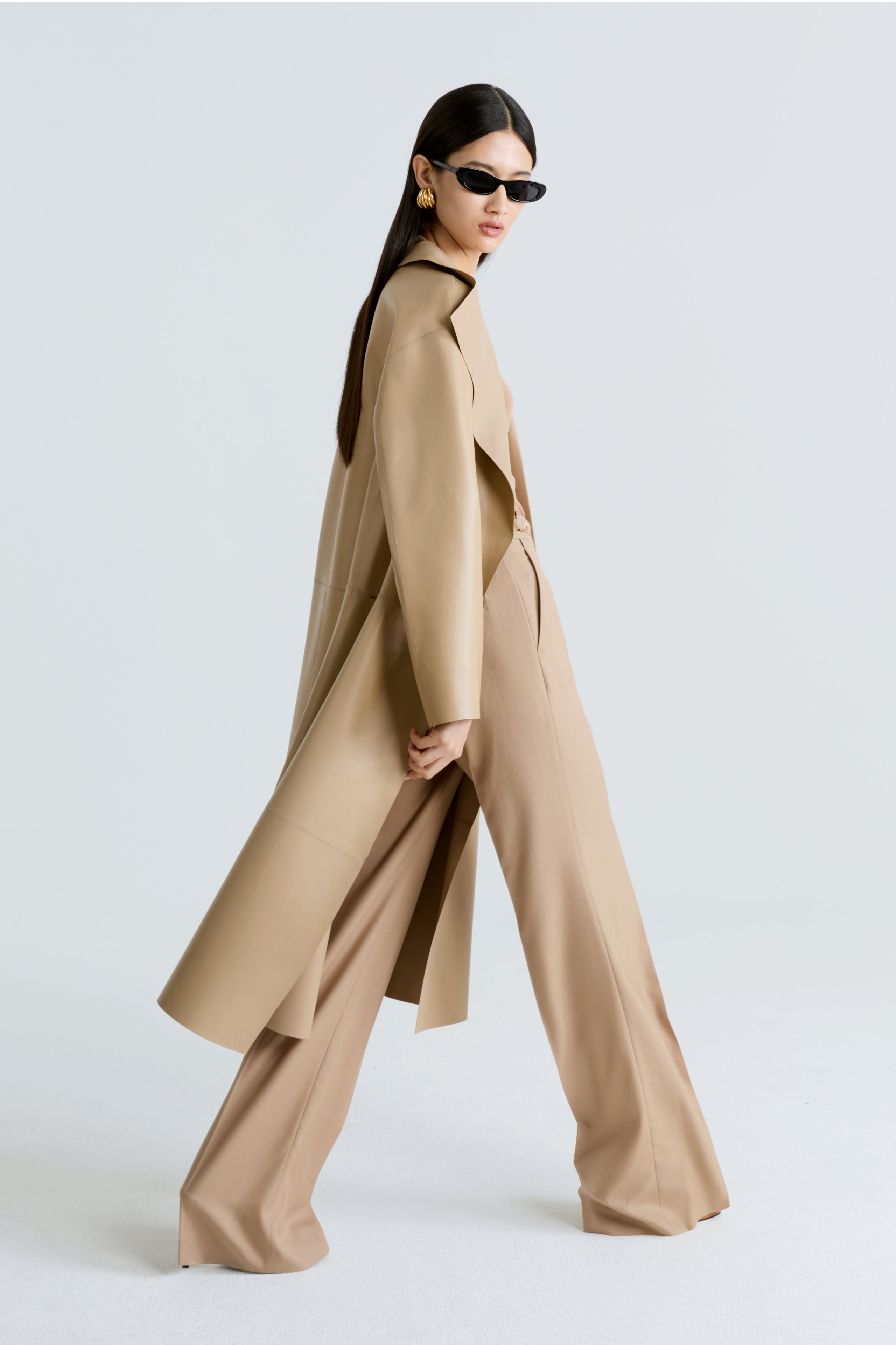 Model is wearing Nour Hammour's Brithday Coat Leather Beige - A Draped Leather Coat - Side Walking