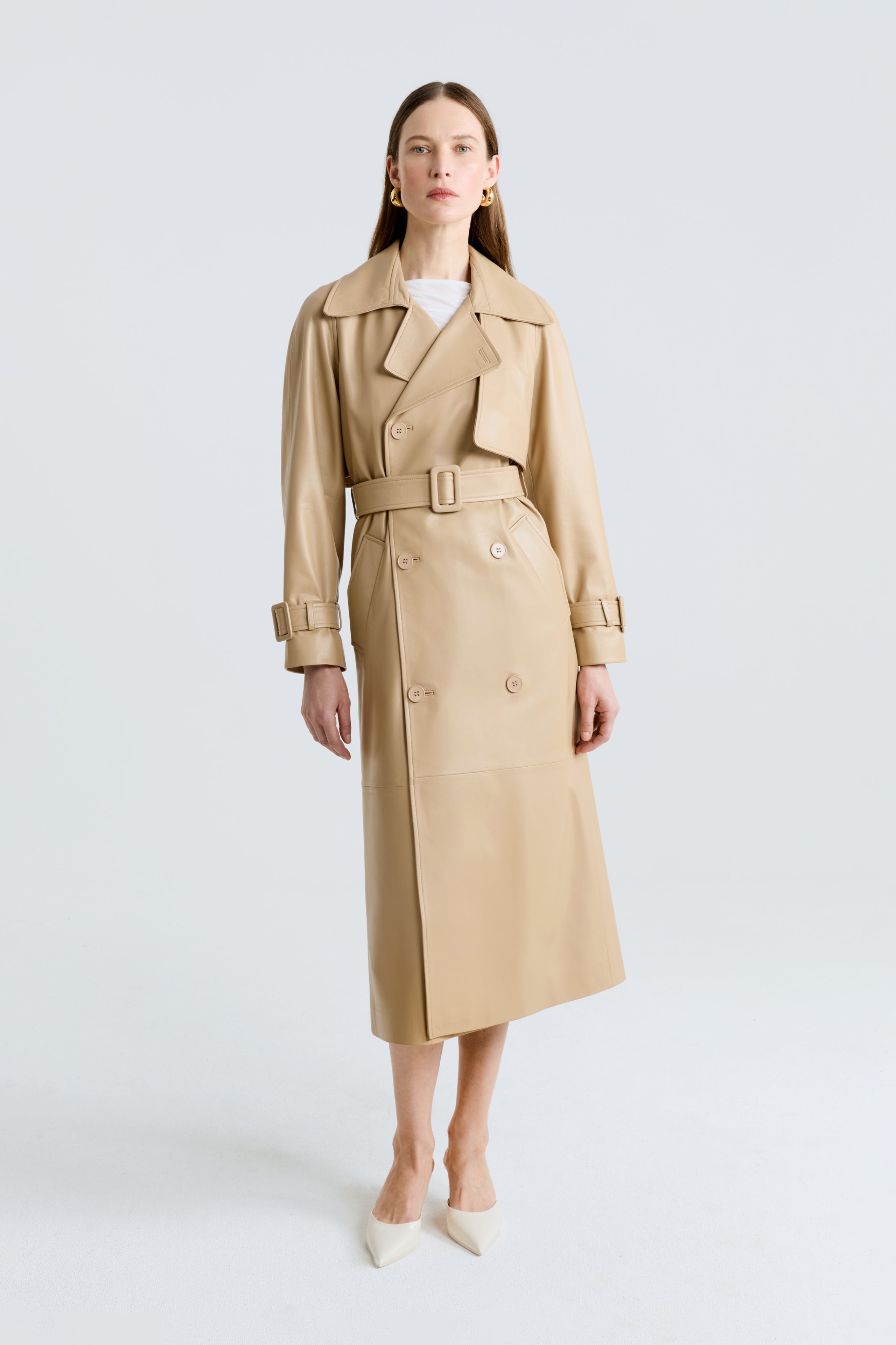 Model is wearing Nour Hammour's Henri Double Breasted Leather Trench Coat in beige - Front  