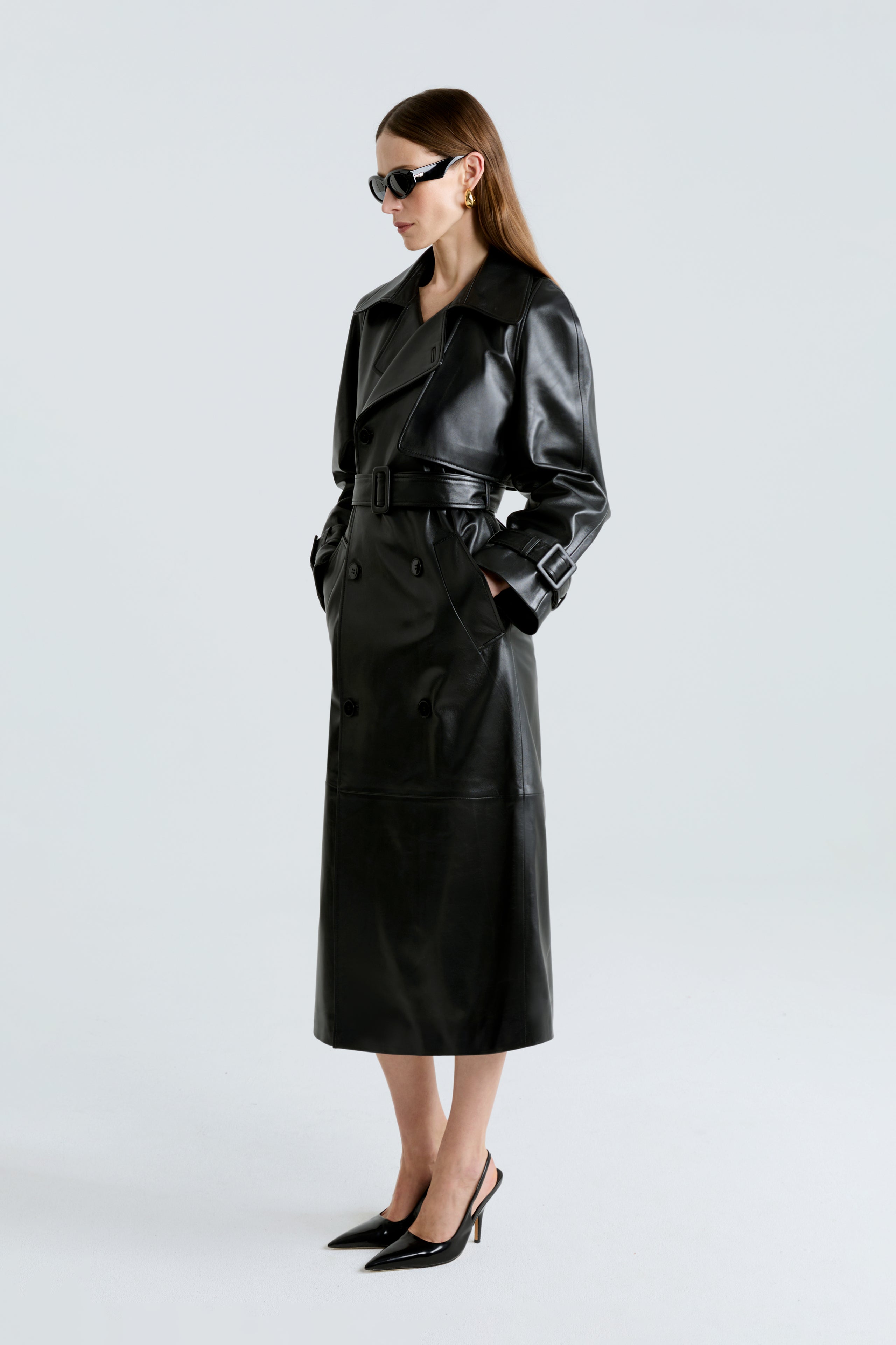 Model is wearing Nour Hammour's Henri Black Leather Trenchcoat - Three-Quarters Closed