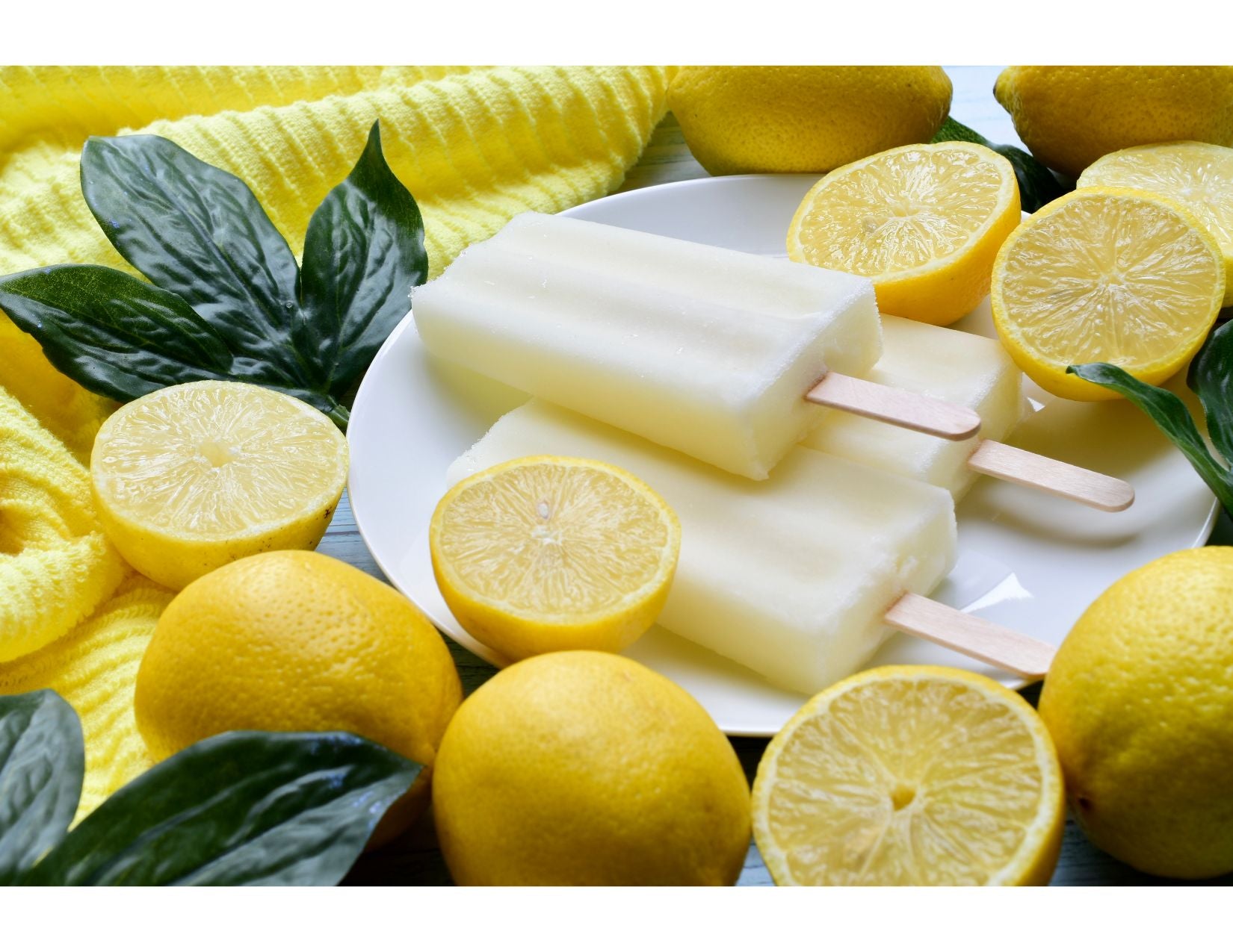 lemon popcicles on a white plate, surrounded by lemons