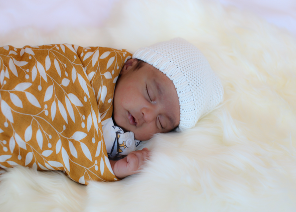 A newborn baby wrapped in a Brolly Sheets Bamboo Swaddle in Autumn Leave Print