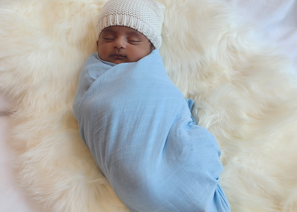 A newborn baby wrapped in a Brolly Sheets Bamboo Swaddle in Dusty Blue