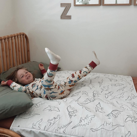 male toddler jumping onto his Dinosaur Print Brolly Sheets with Wings on his bed.