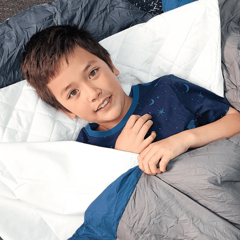 Toddler at school camp using his quilted waterproof sleeping bag liner to protect him discreetly.
