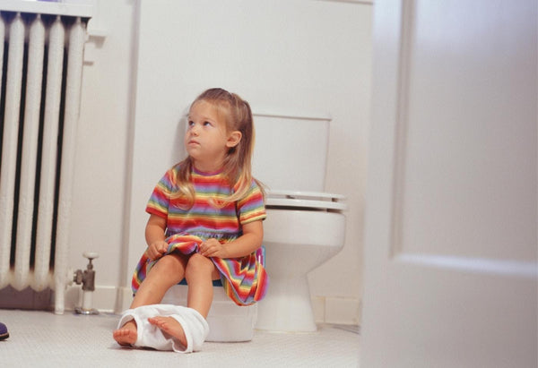 little girl stubbornly sitting on a potty in the bathroom