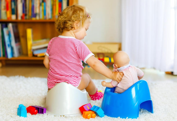 girl on potty in lounge with her baby doll on another potty beside her