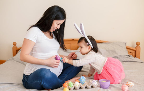 Mum and her young toddler daughter talking about mummy being pregnant