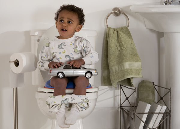 Little male toddler toilet training holding his toy car