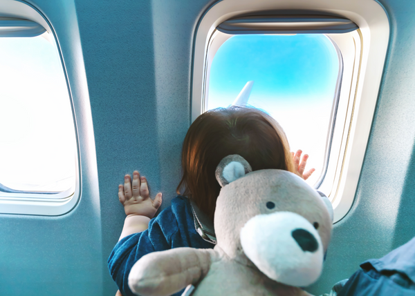 Small toddler child sitting in a good seat on a plane looking out the window