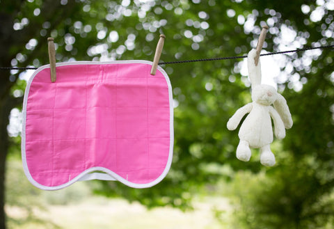 Pink kids car seat protector hanging on washing line