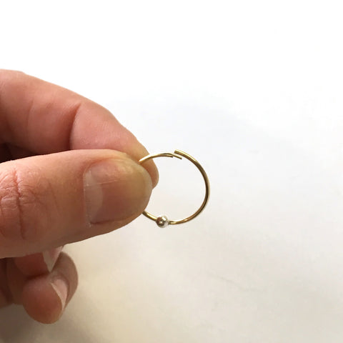 A golden hoop earring opened to show how to put it on 