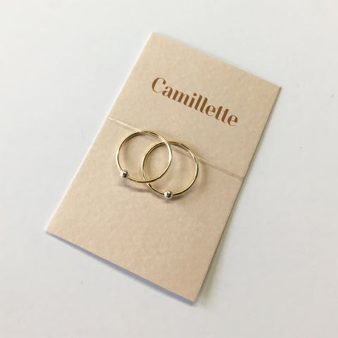 A pair of a Gold Hoop Earrings with silver beads on a cardboard by Camillette