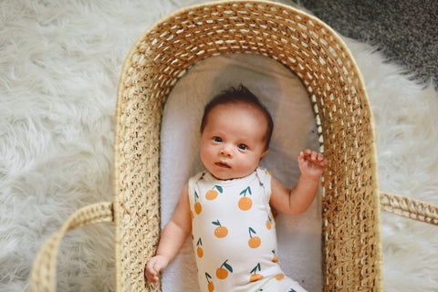 baby in citrus romper lying in moses basket